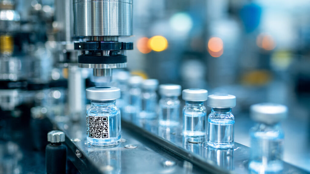 Innovative Pharma Packaging And Labeling Solutions For Efficient Patient Care An automated print and apply labeler attaching serialized labels to pharmaceutical vials on a sterile production line.